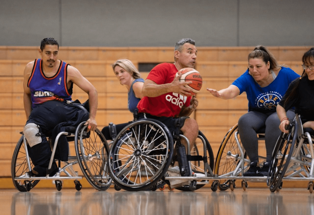 image of Several men and women in wheelchairs playing basketball on an indoor court